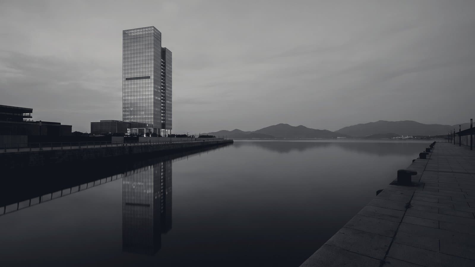 A single tower on a harbour front under flat grey light.