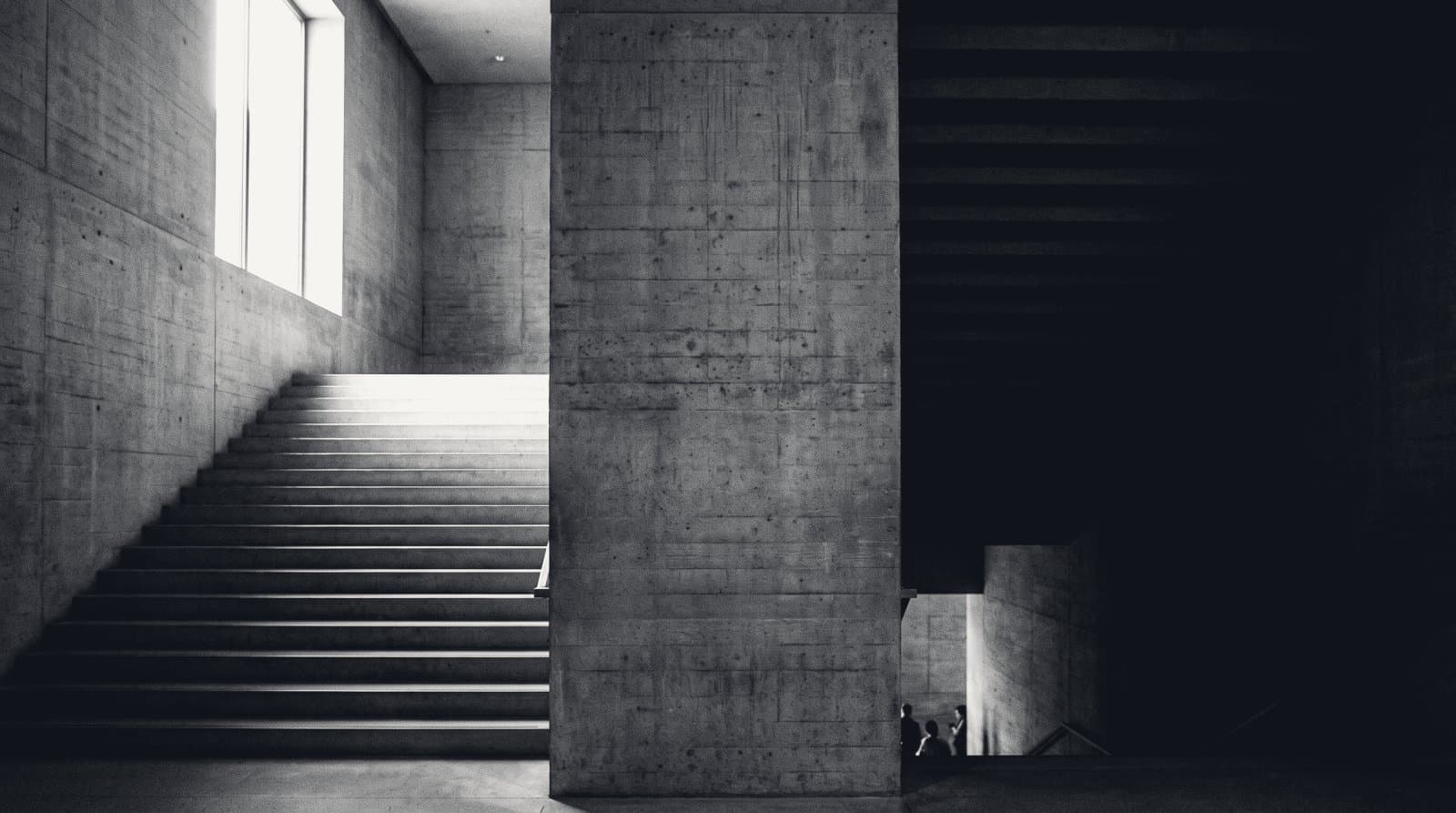 A monumental concrete stair dividing into two flights that climb away from each other.